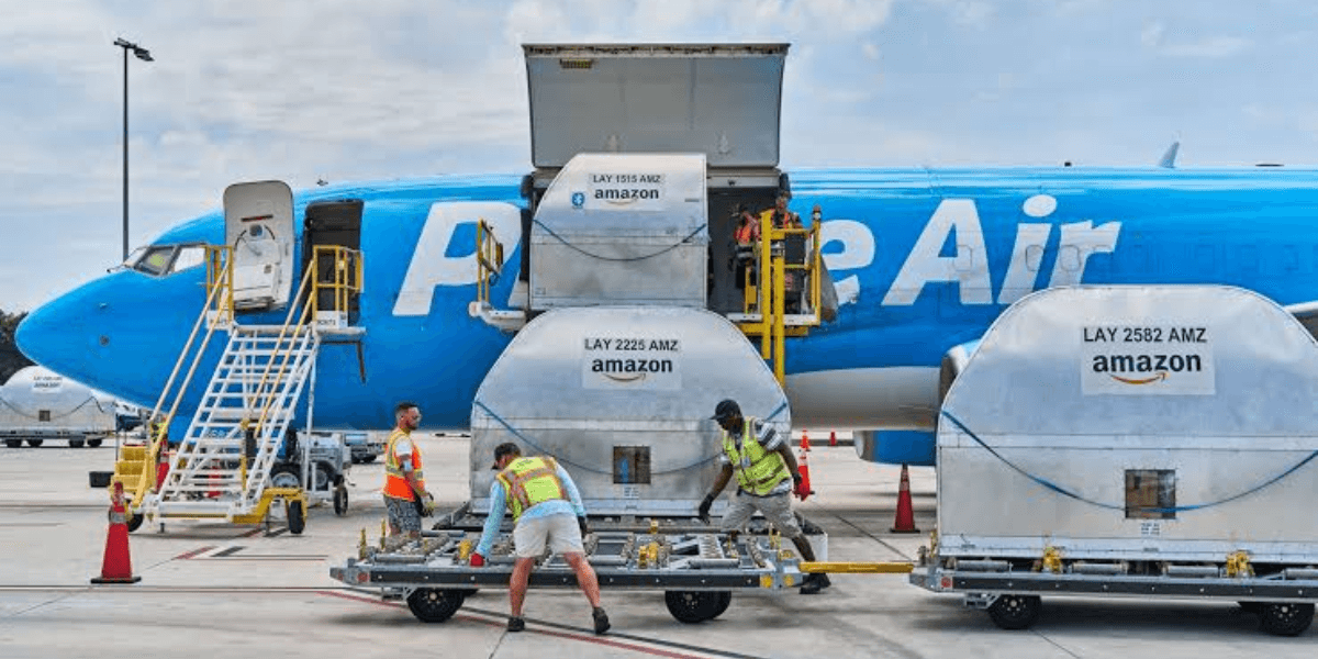 Workers load cargo containers onto a Prime Air aircraft at an airport.