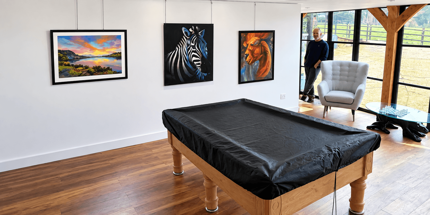 Art gallery interior featuring paintings of landscapes and animals with a billiard table