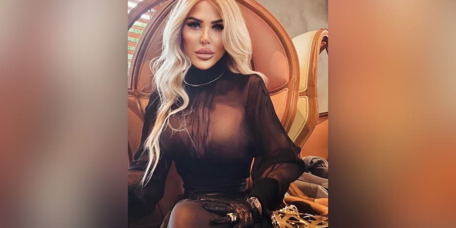 Blonde model sitting comfortably in a luxurious chair, wearing a sheer black top with gloves, exuding a sophisticated and glamorous style.