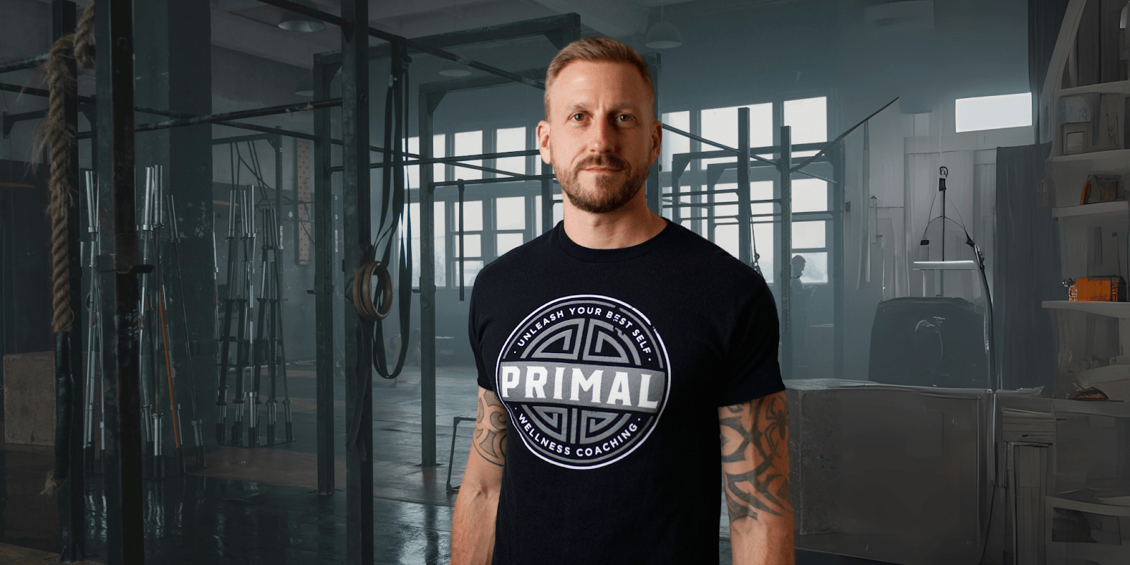 Drew Griesel stands in a gym wearing a Primal Wellness Coaching t-shirt