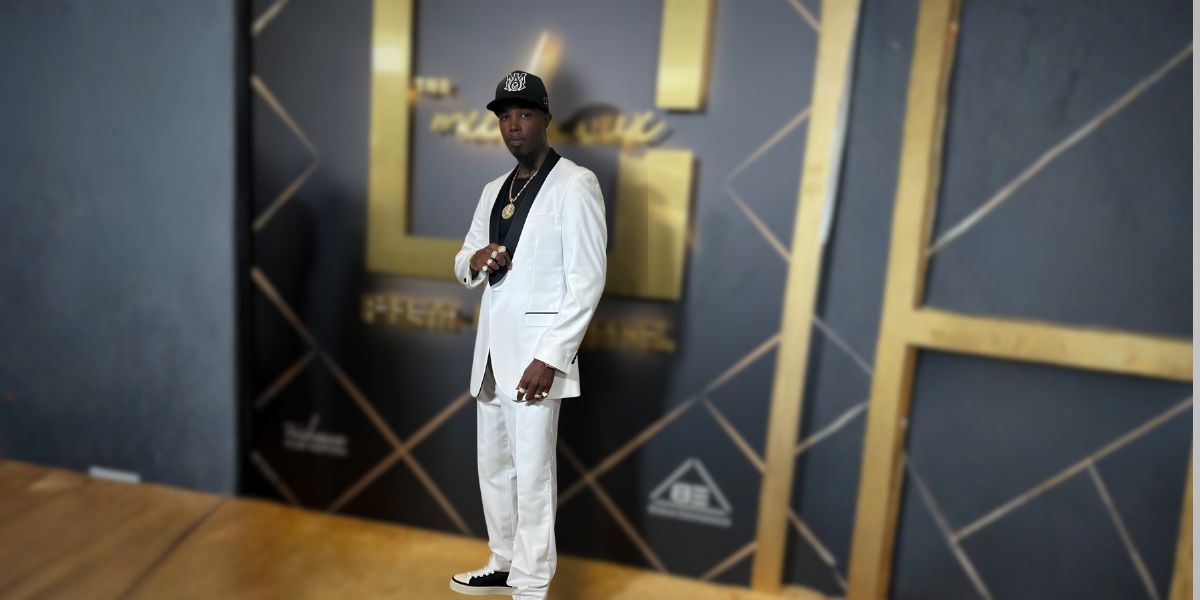 Amazin Jackson in a white suit, standing confidently at an event, showcasing his resilient and purpose-driven legacy.