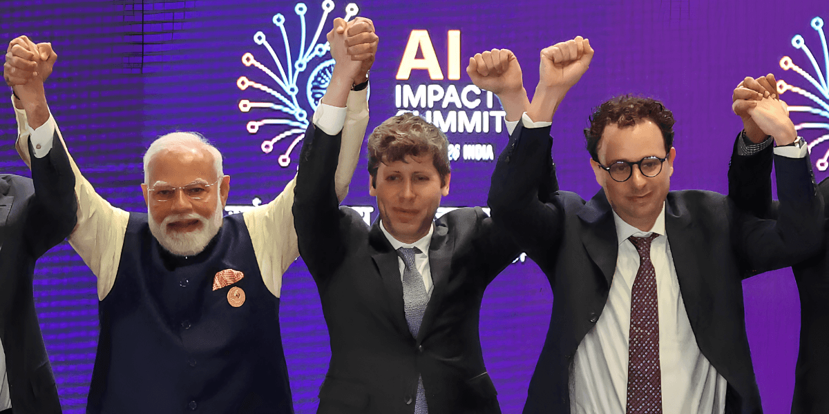 Three individuals raise their arms triumphantly at an AI Impact Summit event