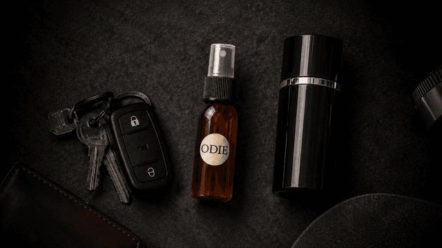 A brown spray bottle labeled "ODIE" alongside car keys and a black container