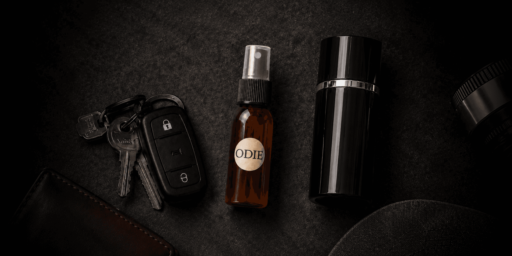 A brown spray bottle labeled "ODIE" alongside car keys and a black container