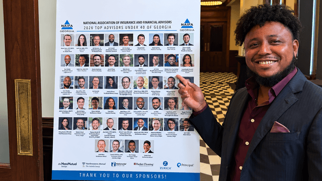 Person smiling while pointing at a poster listing top financial advisors in Georgia
