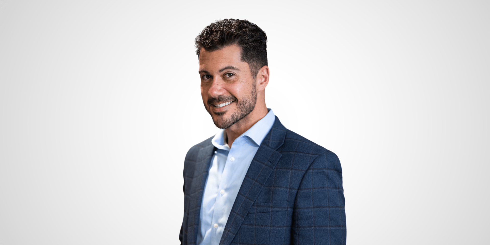 Smiling man in a blue blazer and light shirt against a neutral background