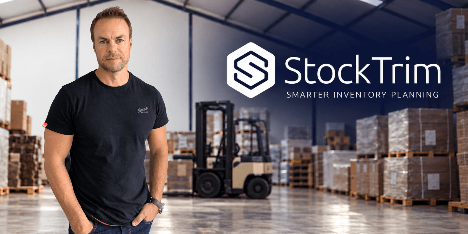 Man standing in a warehouse with inventory shelves and a forklift in the background