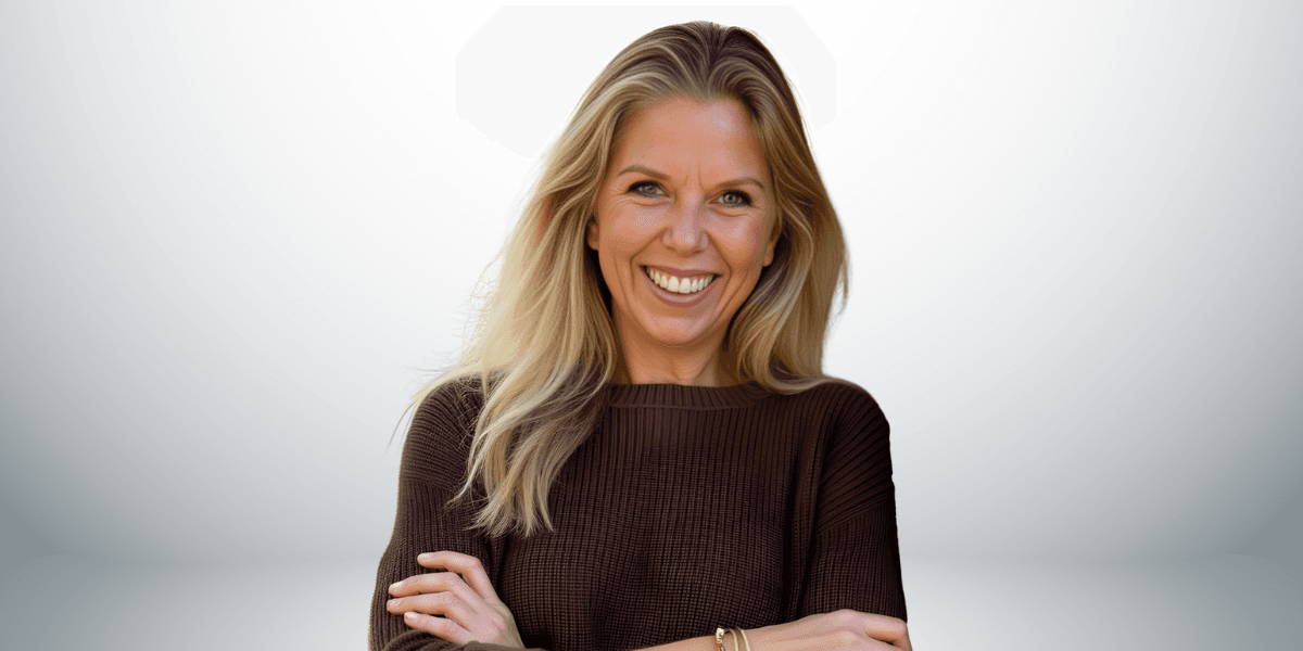 Smiling woman with long blonde hair wearing a brown sweater, arms crossed.