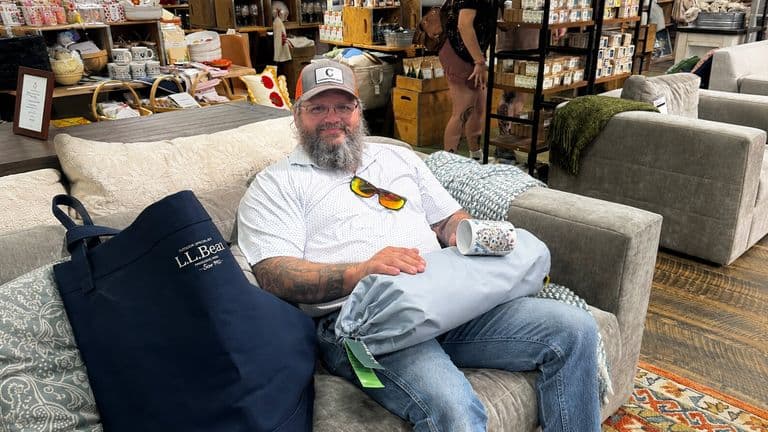 Justin Curatola seated on a sofa in a home furnishings showroom.
