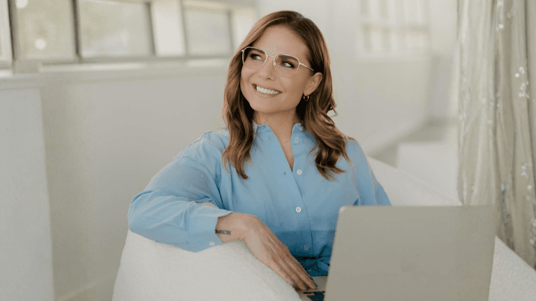 Angela Porrelli sitting with a laptop in a bright office wearing a light blue blouse.