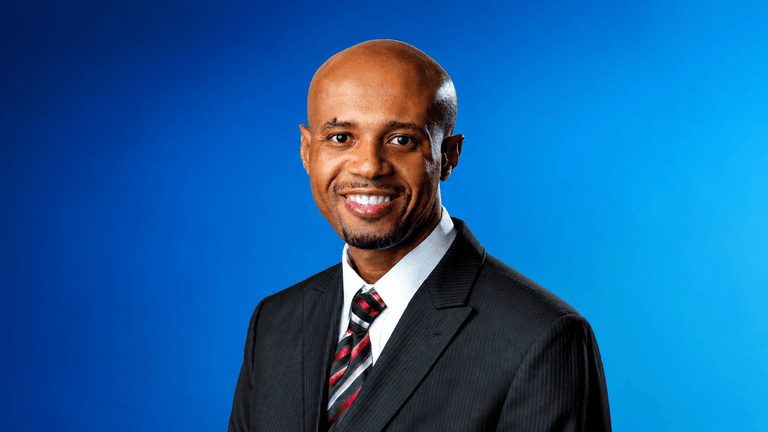 Professional portrait of Dr. Randrick Chance in a business suit against a blue background.